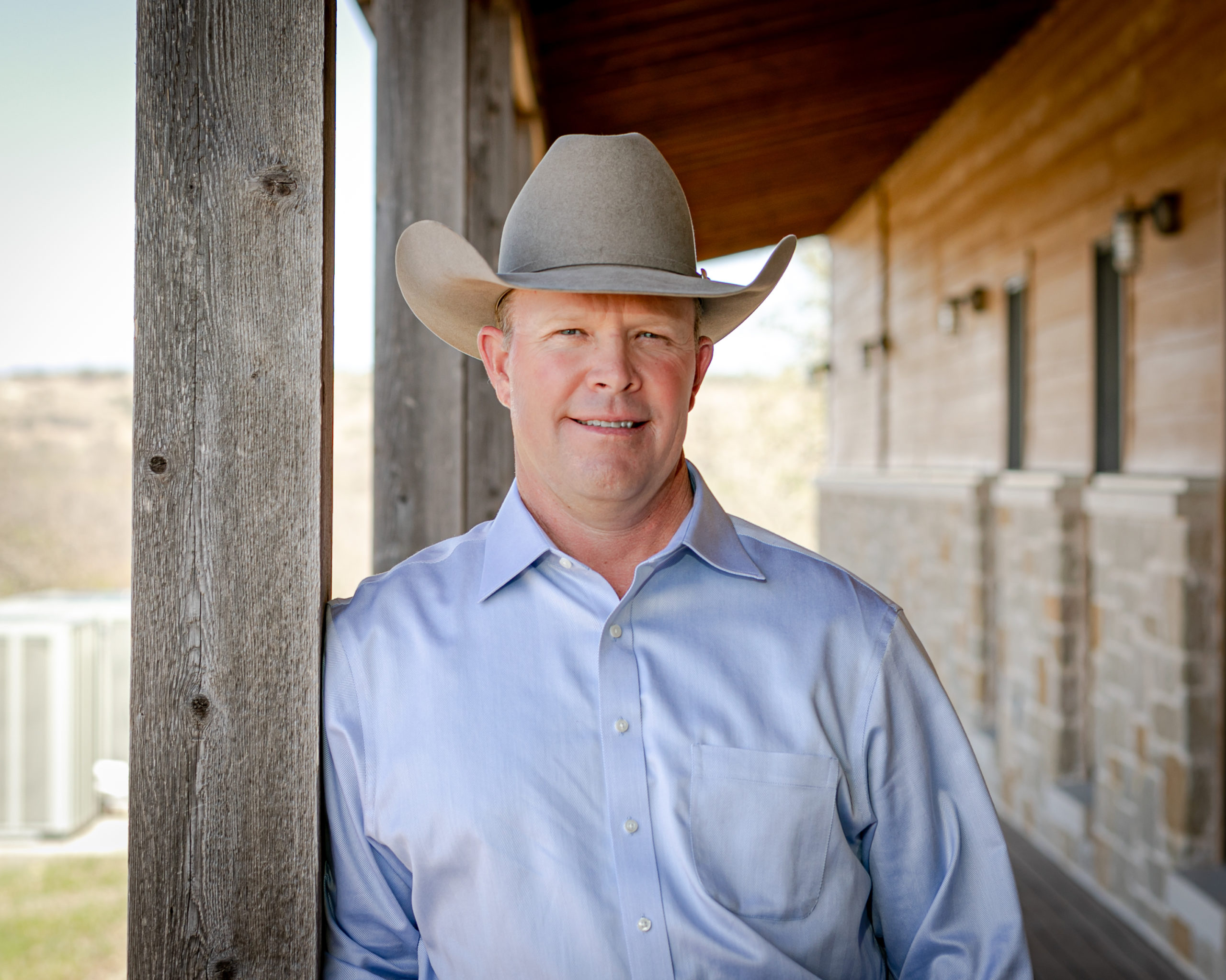 A man in a blue button-up shirt and a cowboy hat. 